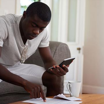 man sitting on couch holding a calculator